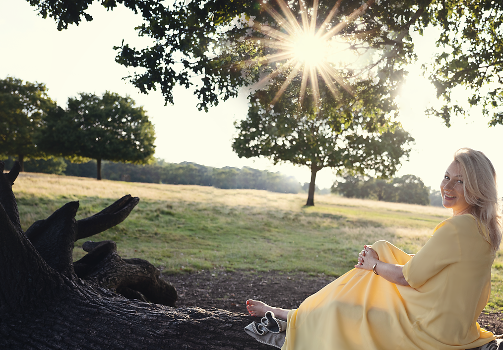 Elizabeth Adams at golden hour, seated beneath an oak in an English meadow